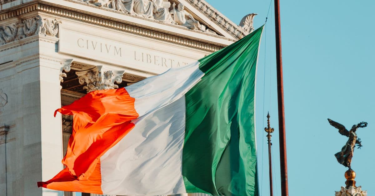 Bandera italiana flameando frente a un monumento histórico en Roma